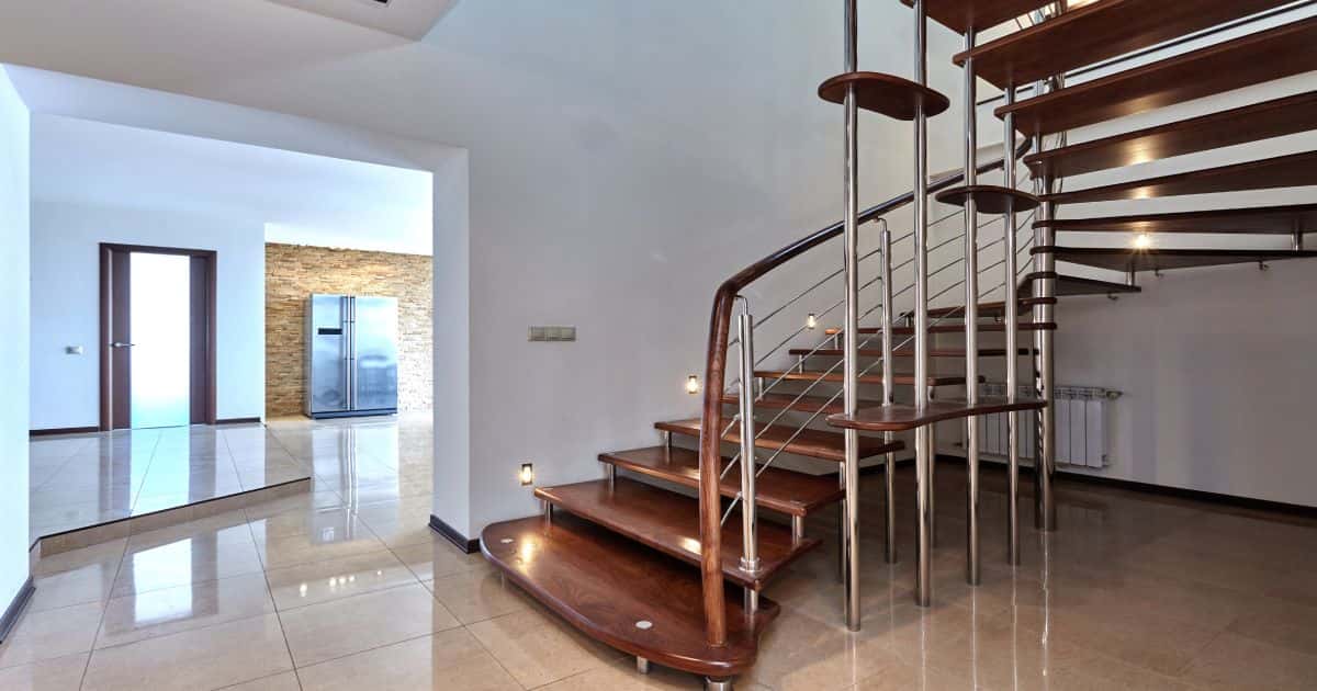 Een halfslagtrap met houten treden, ronde metalen spijlen en een houten trapleuning.