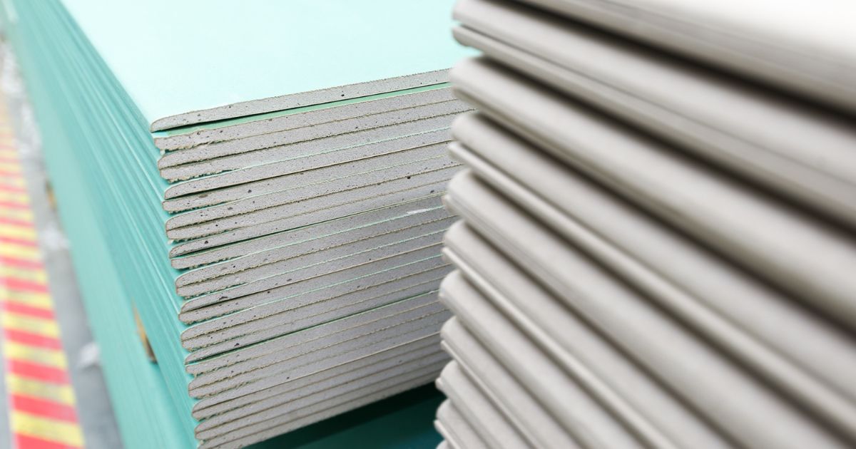 Gestapelde PIR-isolatieplaten met zichtbare geelbruine schuimkern en groene coating, klaar voor gebruik bij spouwmuurisolatie.