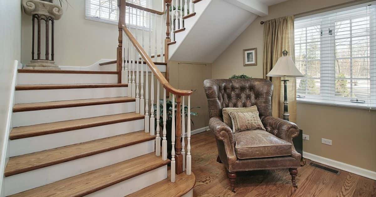 Dichte trap in landelijke stijl met houten treden, witte stootborden en een voorraadkast eronder.