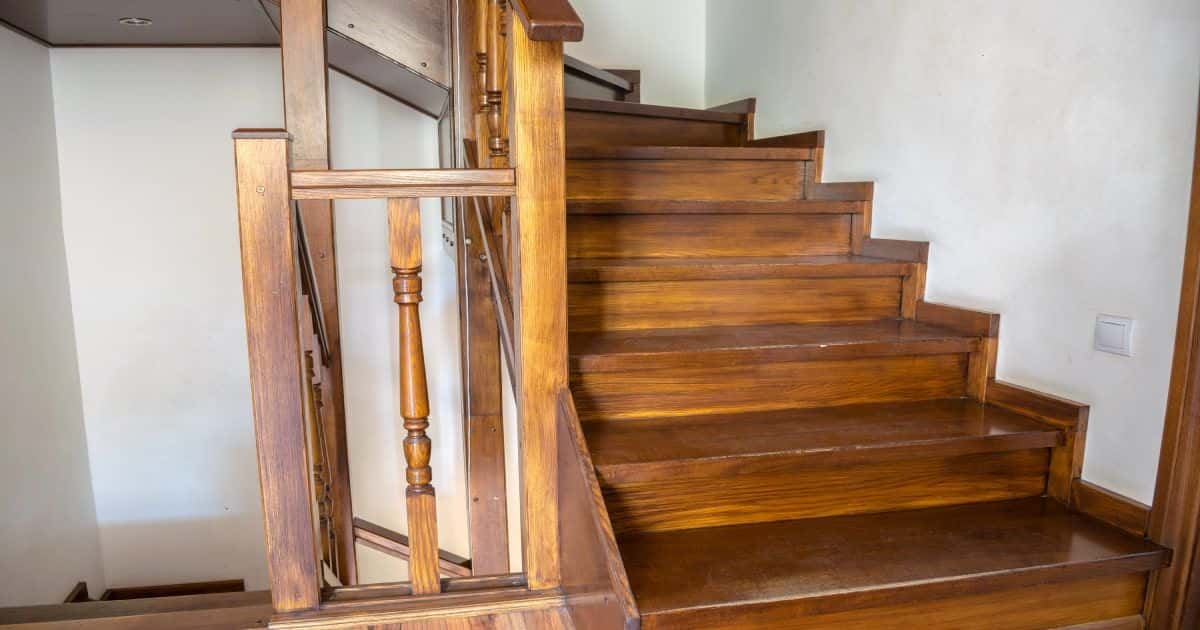 Houten bovenkwart trap in een oud huis. Er is een lichtschakelaar op de muur aan het begin van de trap. 