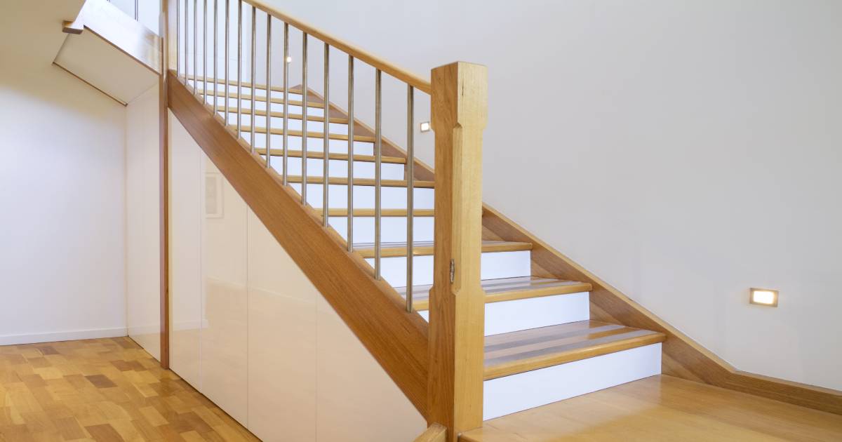 Trap met kwartdraai van 90 graden. De traptreden zijn in hout, terwijl de stootborden wit zijn. Onder de trap bevinden zich inbouwkasten. In de muur naast de trap zijn ook spots ingewerkt.