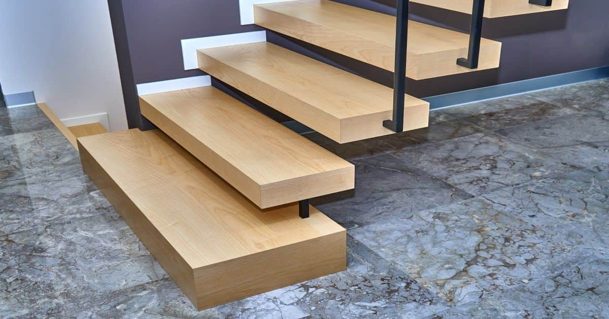 Houten zwevende trap in een huis, met een trapleuning in staal.