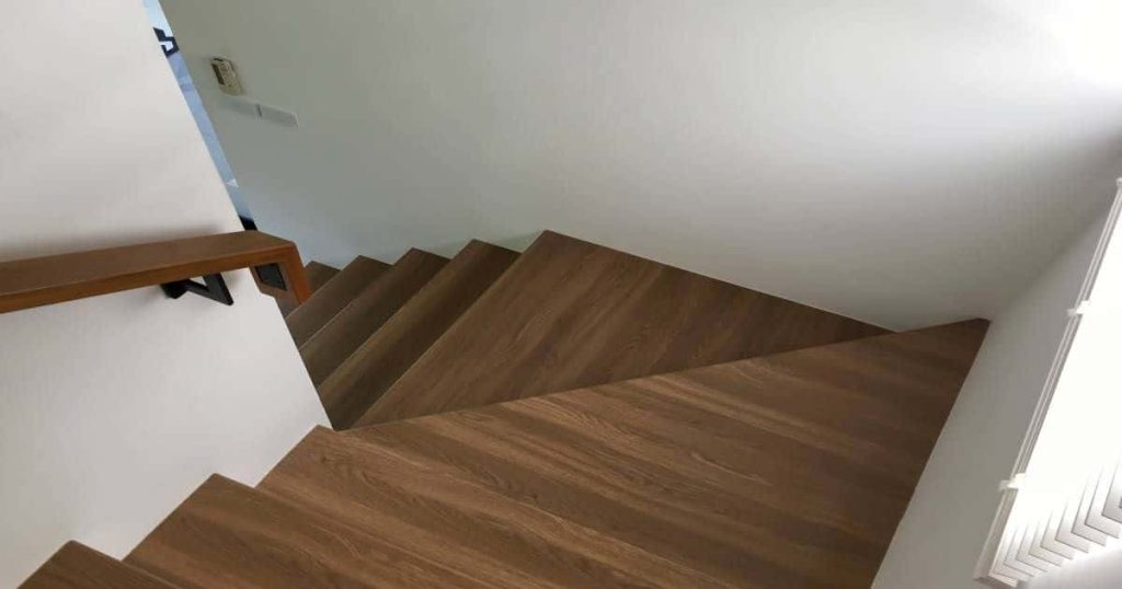 Overzettreden in vinyl met houtlook. Ook de trapleuning is van een gelijkaardige look voorzien.