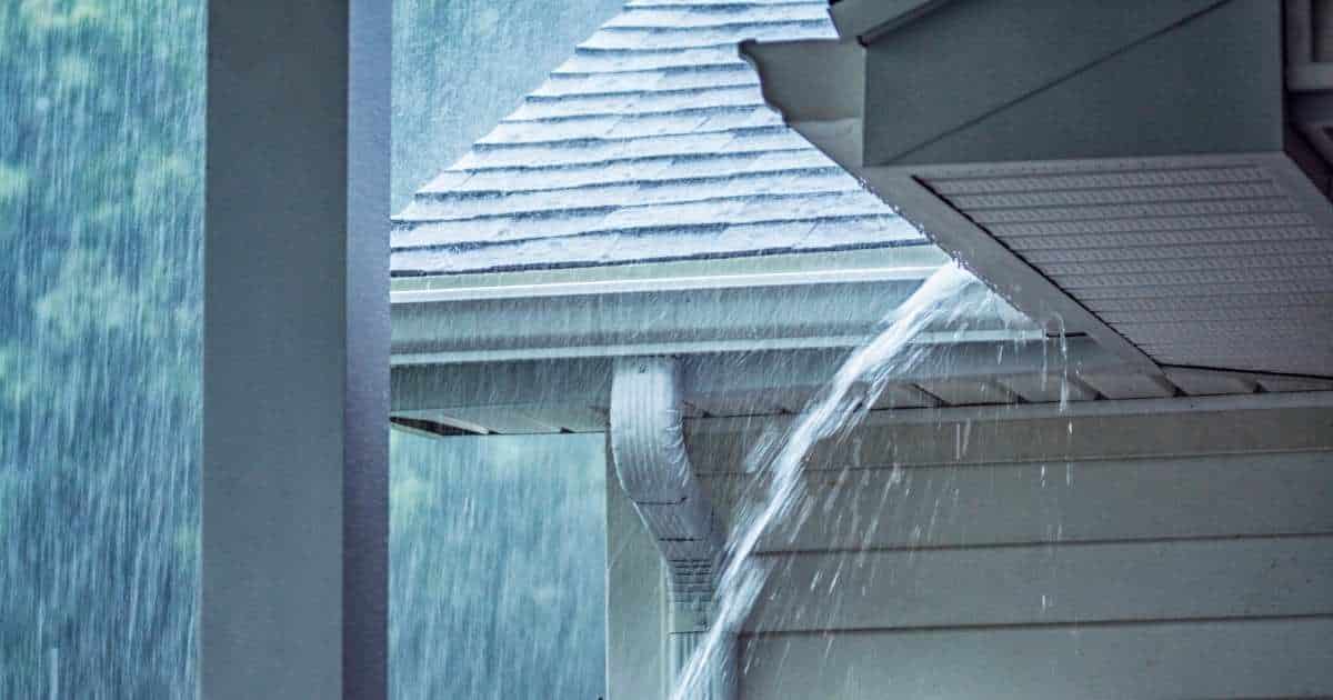 Regenwater stroomt in overvloed van een dak tijdens een regenbui.