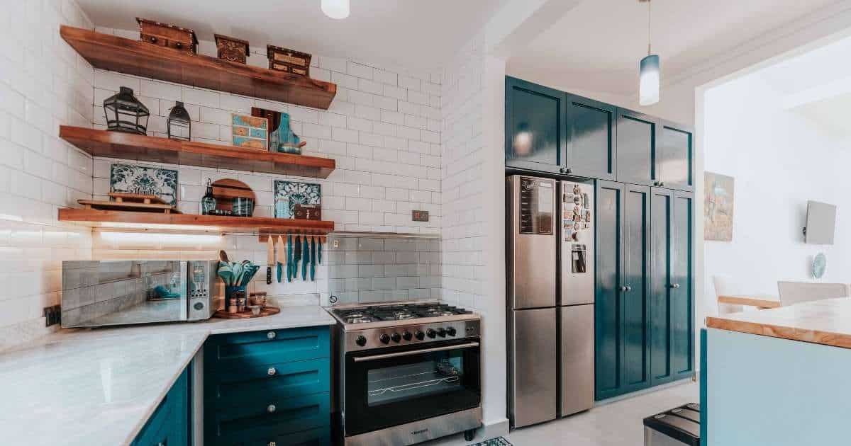 Een keuken met een fraai keukenontwerp: open en gesloten maatwerk kasten, een ingebouwde koelkast, nieuwe oven en stijlvolle keukenkasten met marmer keukenblad.