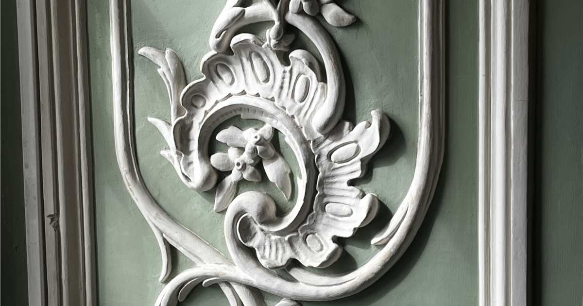 Een groene muur met decoratief pleisterwerk in een bijzondere vorm.