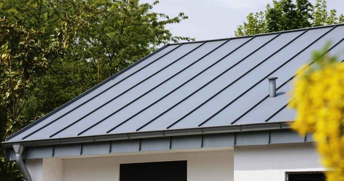 Een witte woning met donkergrijze zinken dakbedekking.