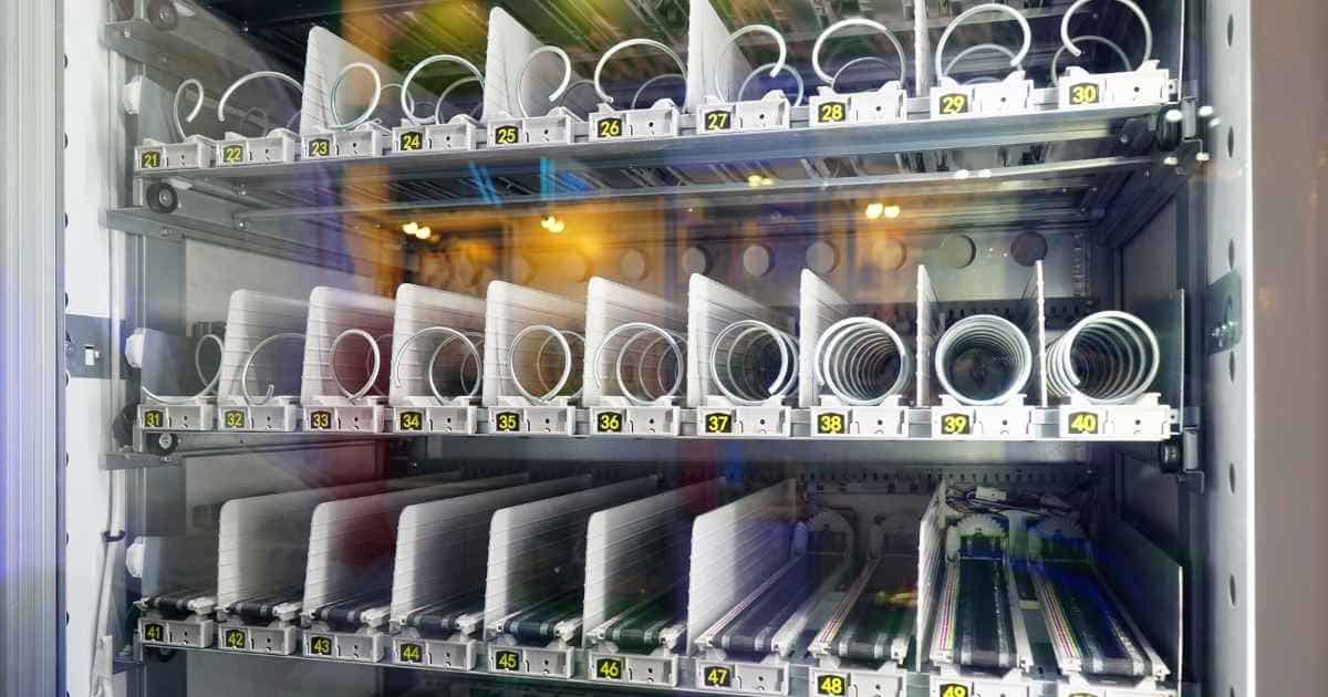 De binnenkant van een leeg automaat voor dranken en snacks. De bovenste 2 rijen zijn voorzien voor snacks, de onderste zichtbare rij voor dranken. Elk vak is voorzien van een nummer.