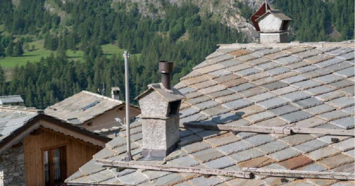 Een authentiek leien dak van natuurleisteen dat uitgeeft op bosrijk gebied met bergen.