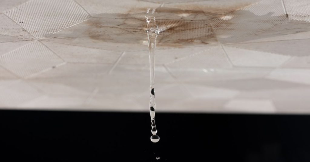 Lekkage opsporen in plafond met bruine vochtvlek en waterdruppels die naar beneden vallen