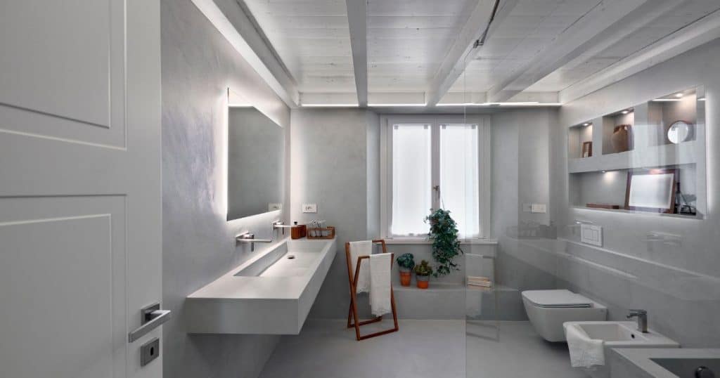 Lichte mortex badkamer met inloopdouche, geïntegreerde wasbak en modern interieur.