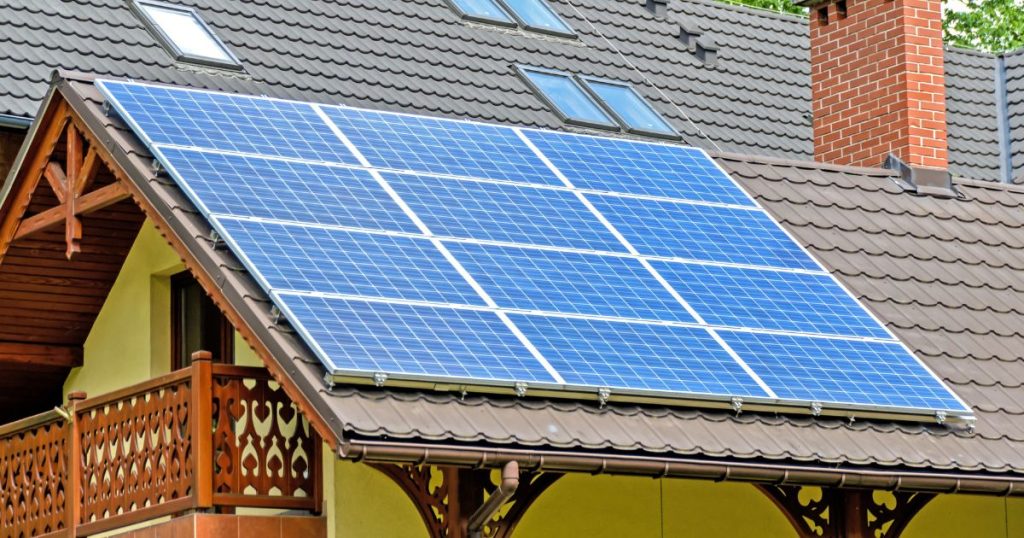 Een dak met zonnepanelen boven een woning met stijlvol, sierlijk balkon.