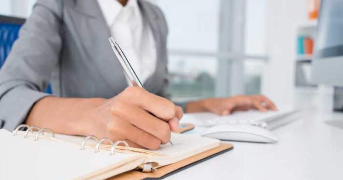 Werkgever die loonkostenberekeningen maakt en aantekeningen noteert in een dossier op kantoor.