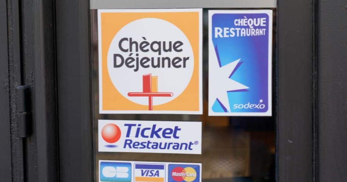De gekende, klassieke logo's van  aanbieders van maaltijdcheques en Ticket Restaurant op de ruit van een horecazaak.