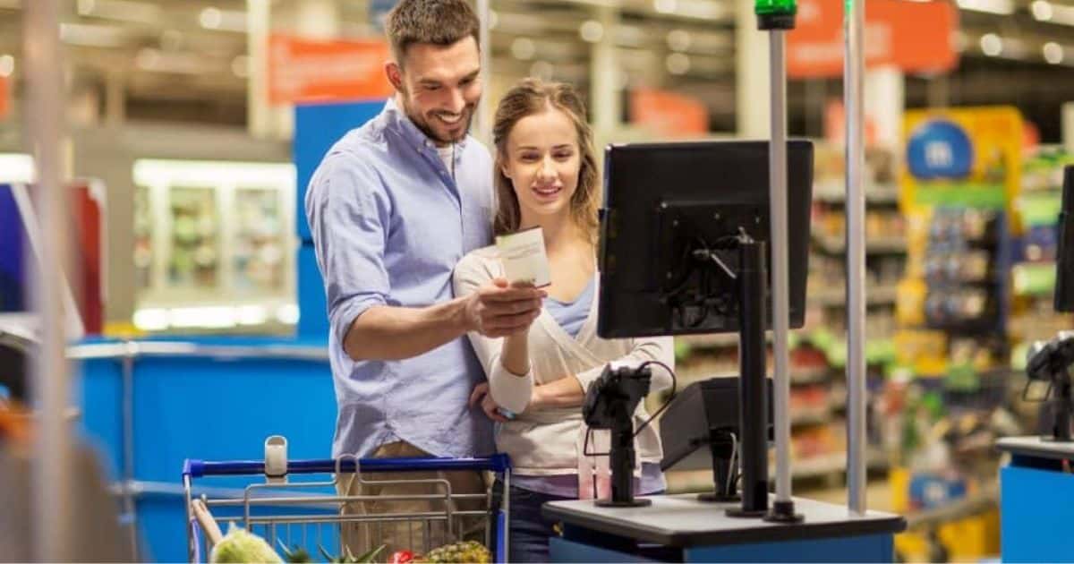 Een jong koppel rekent zelf af in een supermarkt met het onbemande of automatische kassasysteem. Daarna controleren ze nog snel het afgeprinte kassaticket.