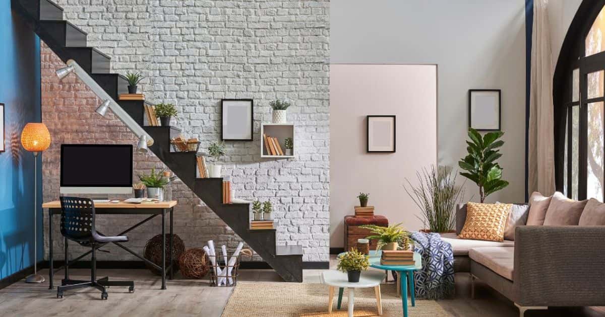 Massief trapontwerp voor industrieel interieur. Op de trap staan planten, net zoals elders in de ruimte om het geheel een zachte, warme uitstraling te geven. Ook opvallend zijn de spots die aan de trap zijn bevestigd voor het bureautje onder de trap.