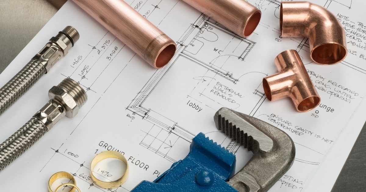 Verschillende herstelstukken en een knijptang: materialen die een loodgieter regelmatig gebruikt. Het materiaal ligt op een schematisch overzicht van een woning.