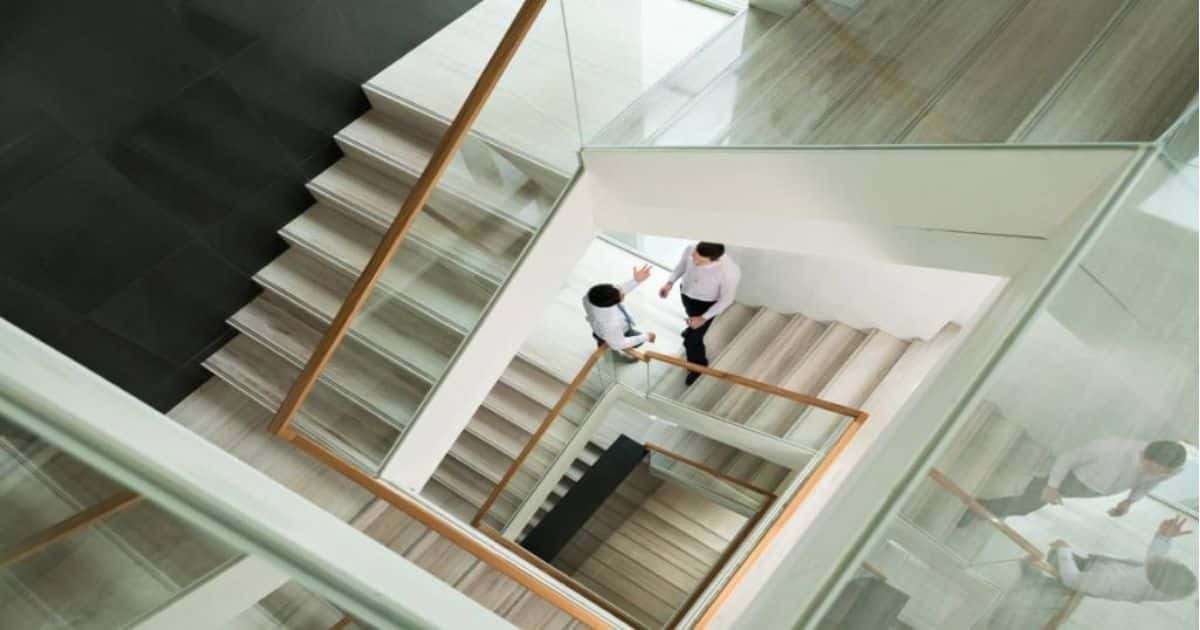 Meerdere verdiepingen van dubbele kwartslagtrappen met houten leuningen en glazen balustrades