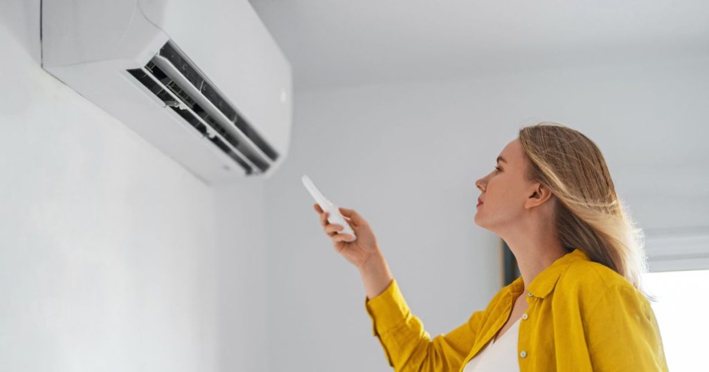 Een jonge vrouw bedient haar airco voor de eerste keer na de installatie.