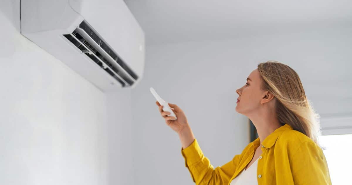 Een jonge vrouw bedient haar airco voor de eerste keer na de installatie.