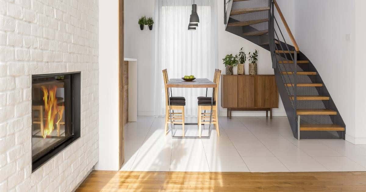 Wenteltrap met houten treden in een eerder kleine woonkamer. Er is een ingebouwde openhaard aanwezig. 