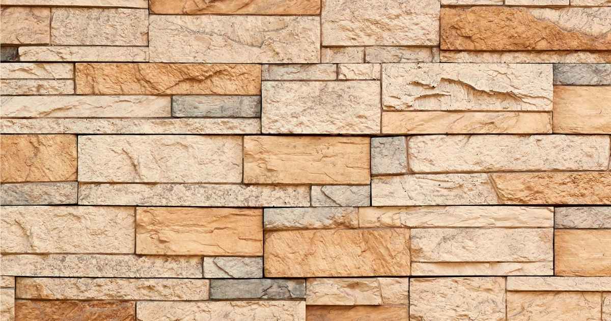 Een gemetselde muur uit gele en grijze zandsteen.