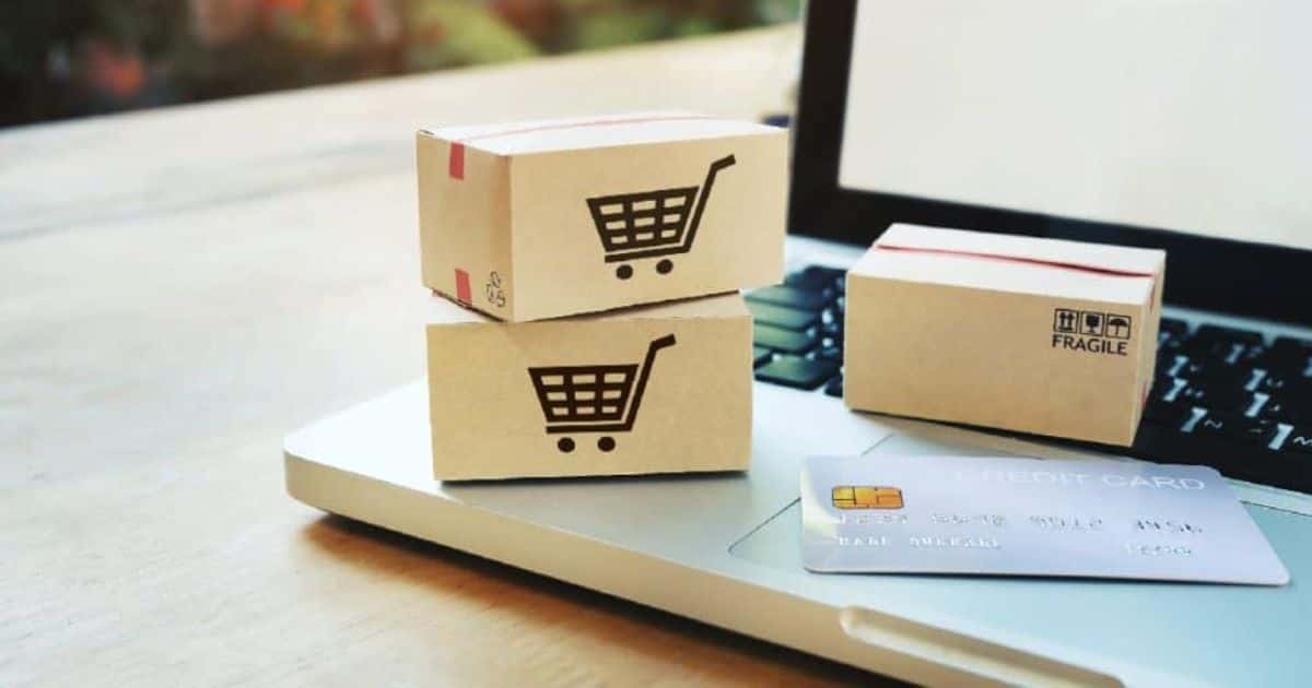 Een laptop waarop enkele kleine pakketjes en een kredietkaart liggen.