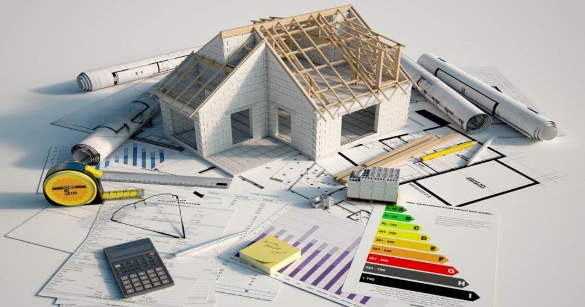 Modelwoning op bouwplannen met energielabel, meetlint, rekenmachine en technische tekeningen.
