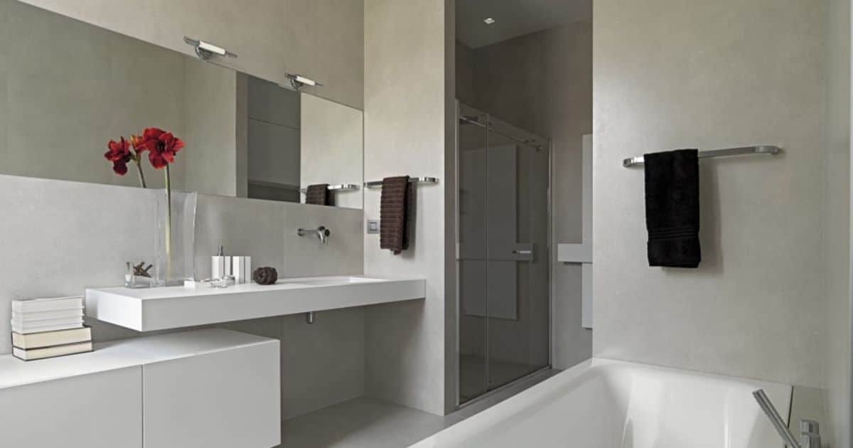 Moderne badkamer met grijze wanden, een grote spiegel, witte zwevende wastafel, inloopdouche met glazen schuifdeur en een ligbad.