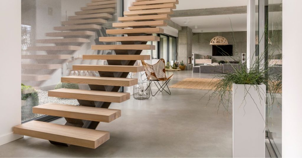 Een moderne zwevende trap met zwarte stalen trapboom en beuken traptreden in een minimalistisch interieur.