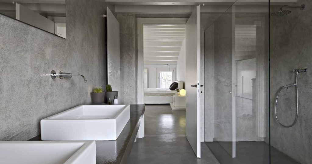Moderne mortex badkamer met grijze wanden, inloopdouche en witte wastafel in strak design.
