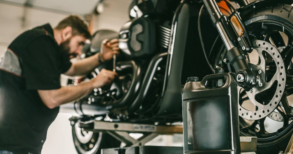 Een man repareert een motor. De kosten zijn vergoed door de motorverzekering van de eigenaar.
