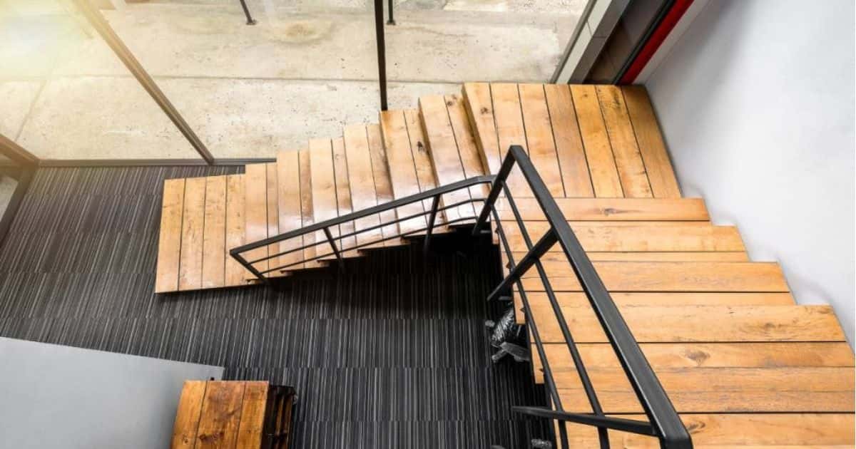 Onderkwart trap met houten treden, stootborden en een zwarte metalen leuning