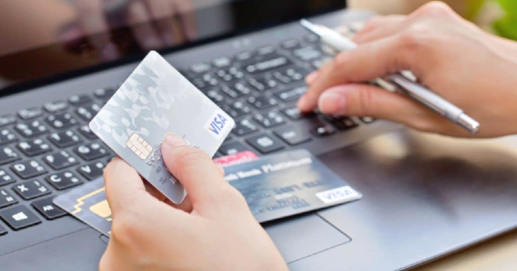 Een dame gebruikt haar VISA kaart om een online transactie te voltooien op haar zwarte laptop.