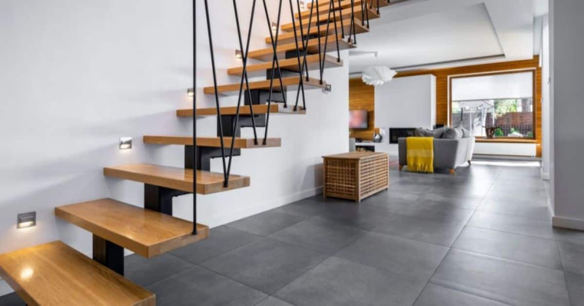 Open houten trap waar lichtjes op schijnen. Er is ook een grijze zetel met een geel deken. 