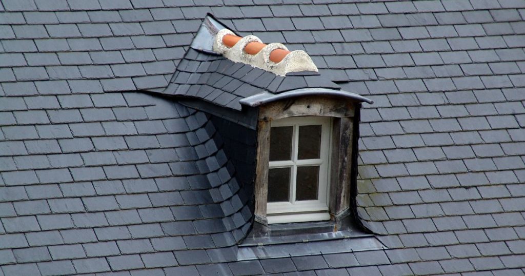 Een oude bestaande dakkapel op een tegelpannendak die men dringend moet laten isoleren om warmteverliezen te voorkomen.