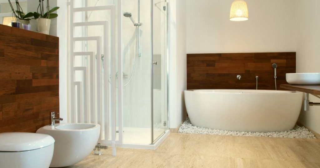 Een moderne badkamer met parket, een wit bad, een bidet en een douchecabine.