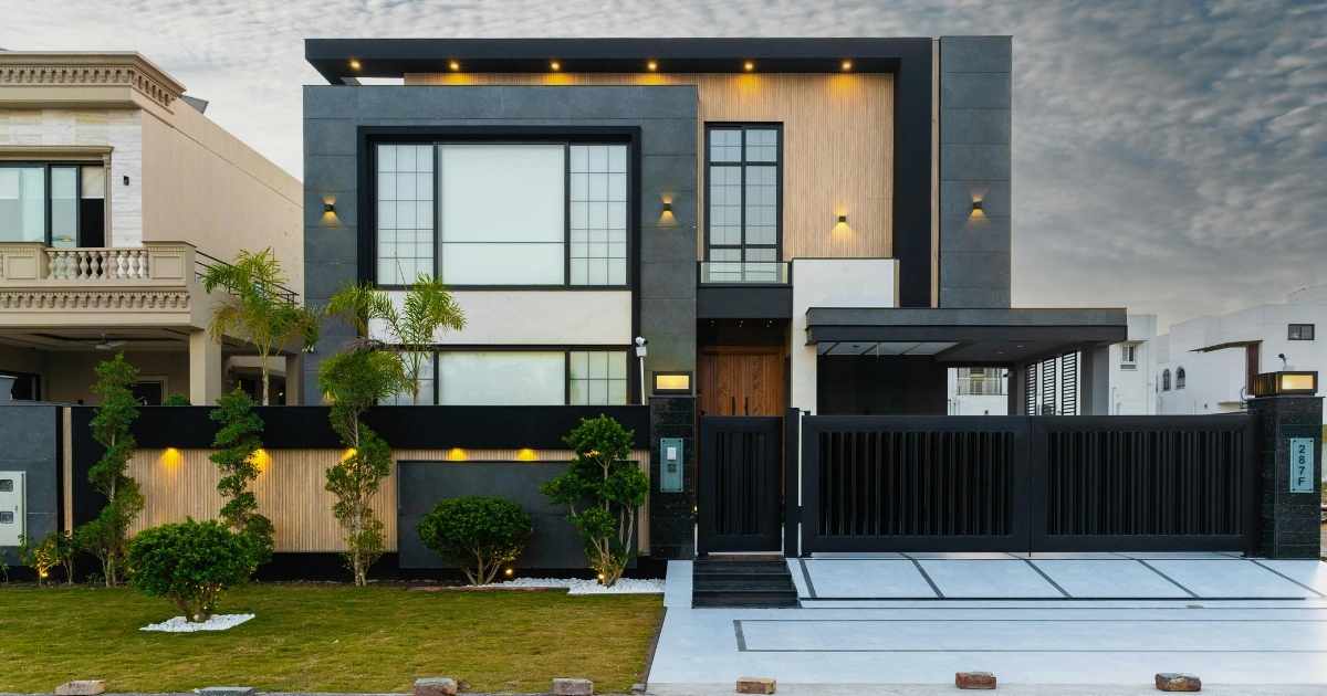 Een moderne woning met plat dak, omheinde tuin en grote poort.