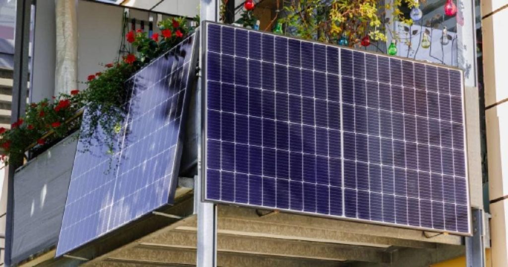 Twee plug and play zonnepanelen bevestigd aan een balkon met veel bloemen. 