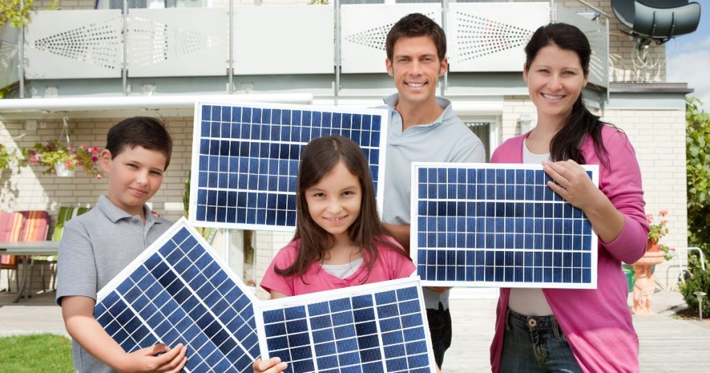 Een gezin met moeder, vader, dochter en zoon: elk gezinslid houdt een klein plug-in zonnepaneel vast.