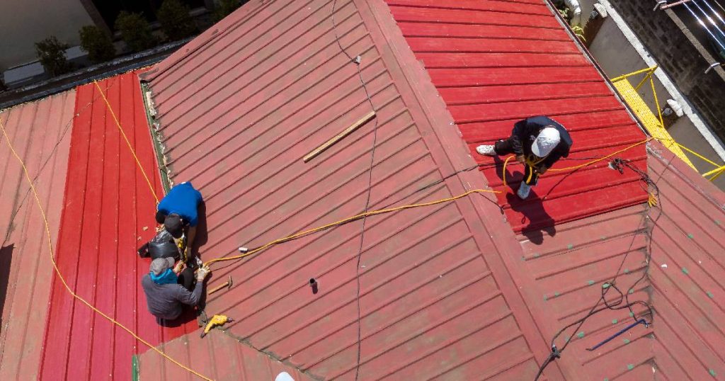 Drie dakwerkers voorzien een dak van nieuwe waterdichte dakbedekking: een dakrenovatie waarvoor de eigenaar van de woning een premie kan aanvragen.