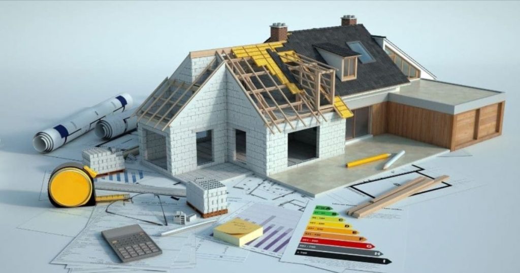 Een maquette van een huis dat deels nog gebouwd wordt. Om de maquette heen liggen enkele papieren met grafieken, een EPC-label grafiek, potloden, meetlatten, een bril en een rekenmachine.