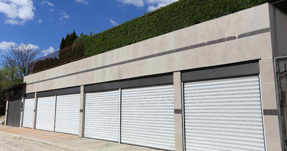 Een betonnen garagebox met drie garages en een plat dak.