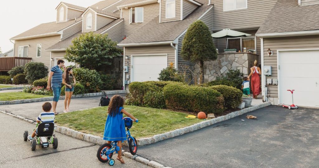 Een straat met huizen met recent geïsoleerde daken waar verschillende buren en hun kinderen samenkomen.