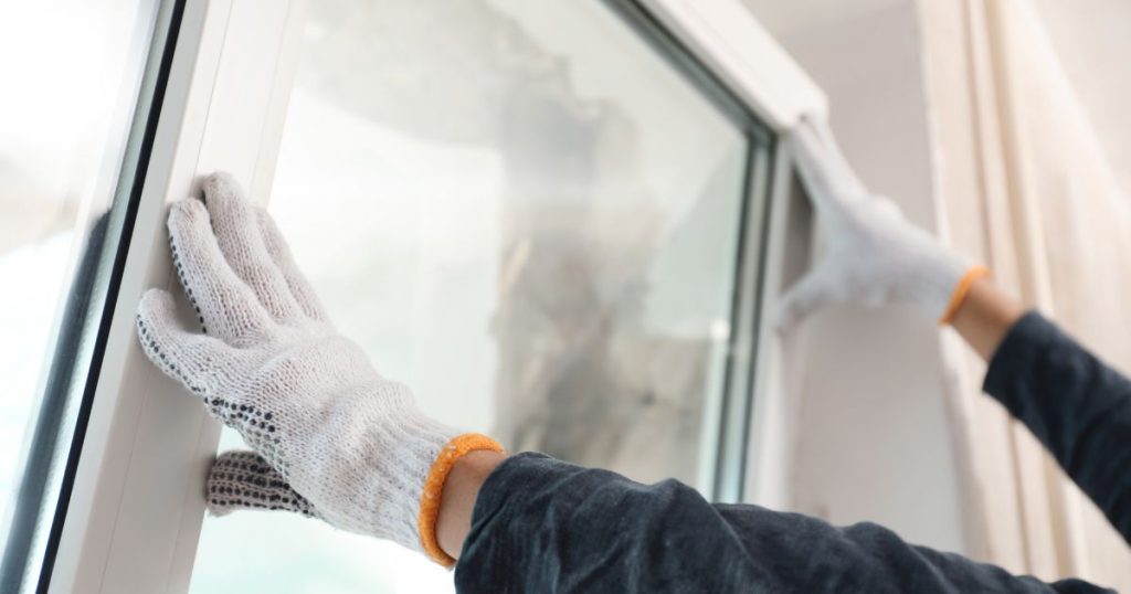 Een specialist is druk in de weer met het vervangen of renoveren van de ramen en deuren van een woning.