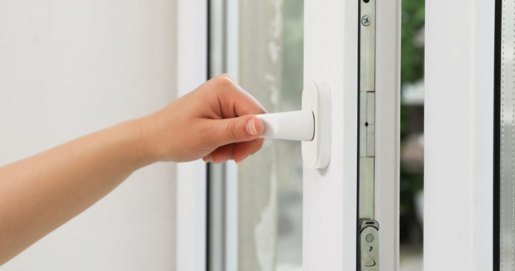 Een pvc kantelraam in een woning waar men net de ramen en deuren heeft laten vervangen of renoveren. De bewoner test of het nieuwe raam goed opent en sluit.