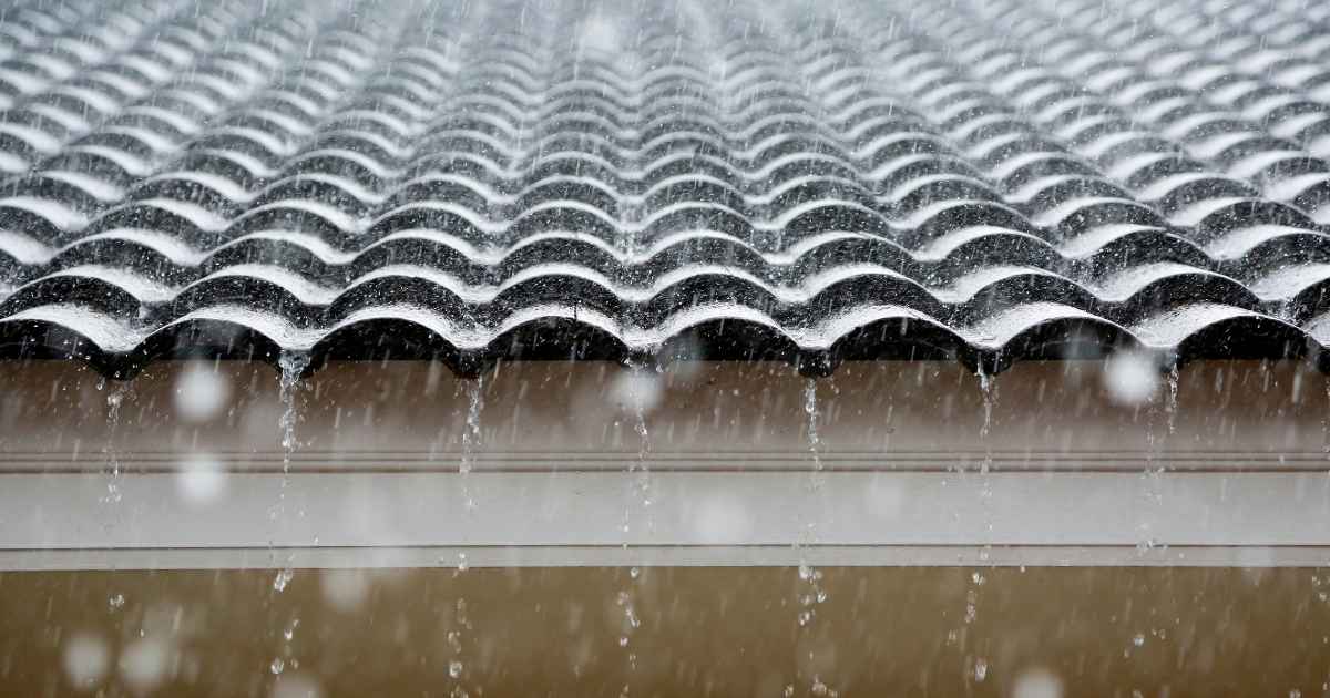 Een dak met holle dakpannen tijdens een regenbui.