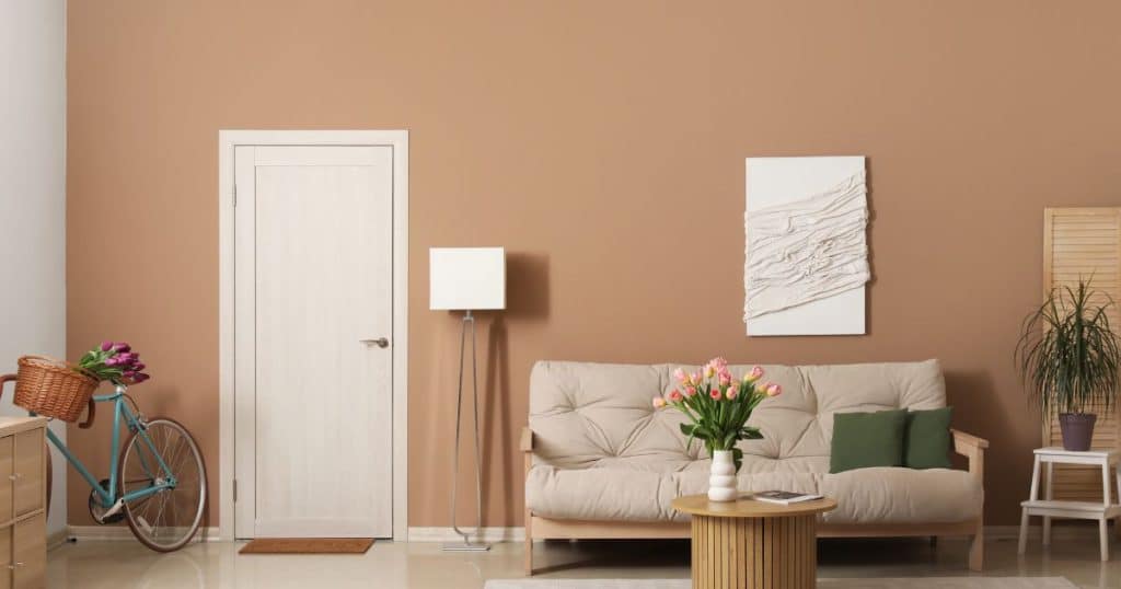 Een kleine kamer met roze accentmuur en witte zijwand. In de kamer staan een fiets, sofa, bijzettafel en andere decoratie.