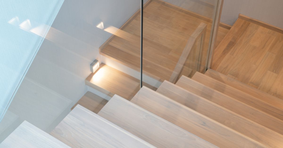 Elegante, lichte en moderne landelijke trap, met een glazen wand als scheiding tussen de 2 trapdelen.