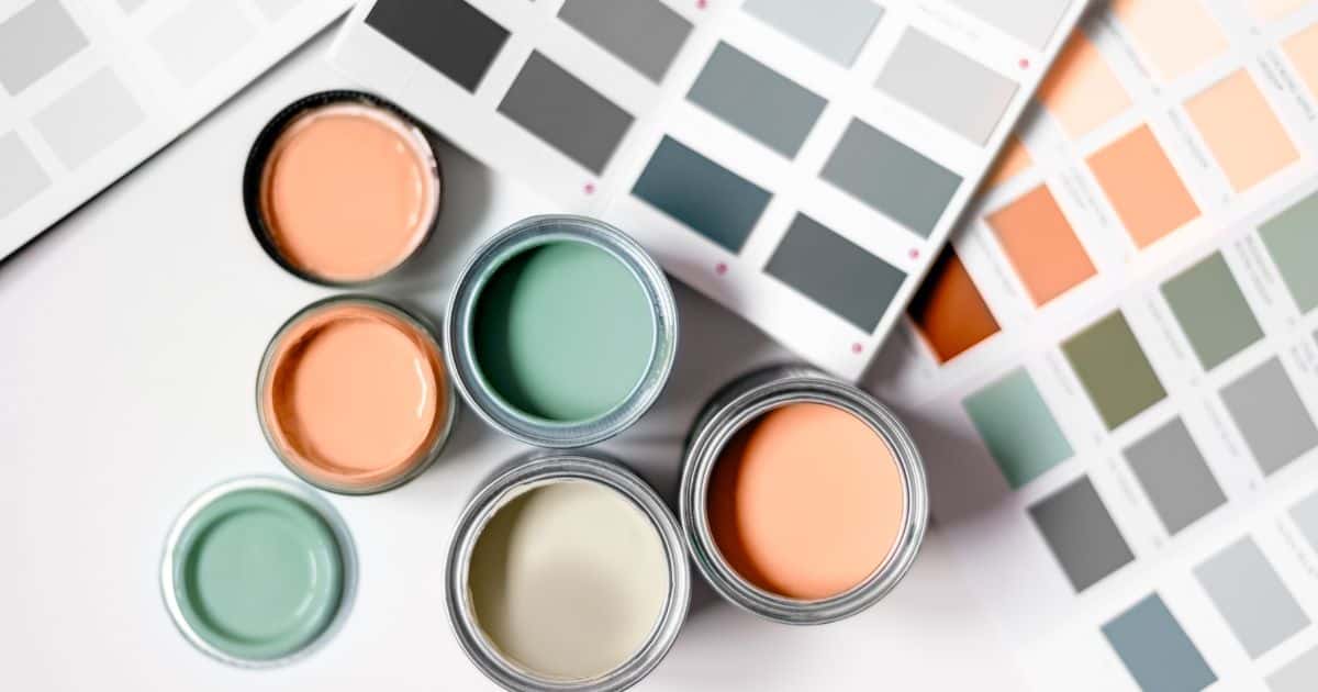 Kleurstalen op papier en 3 verfpotten met bijhorend deksel: roze-oranje, groen en beige.